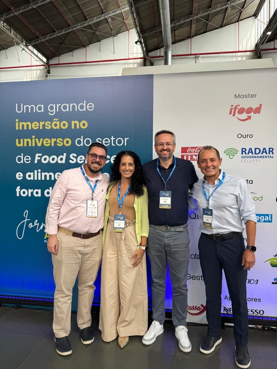 Um grupo de pessoas está posando para uma foto em frente a uma parede.