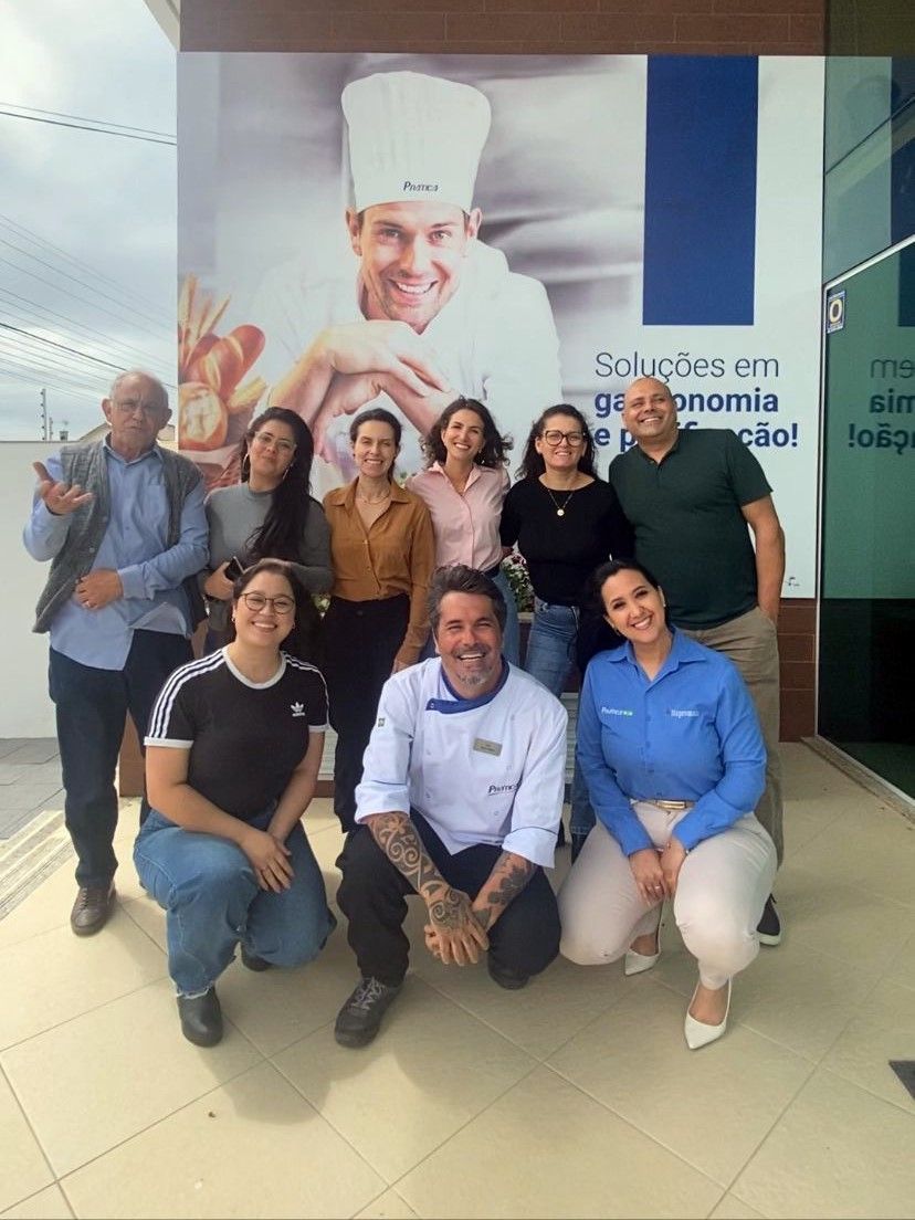 Um grupo de pessoas posando para uma foto com um chef ao fundo