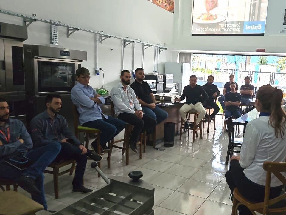 Um grupo de pessoas está sentado ao redor de uma mesa em uma sala.