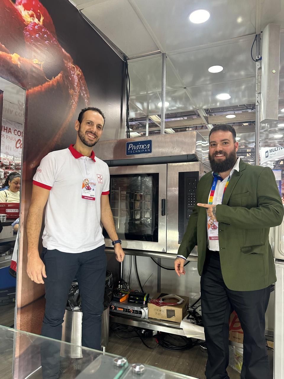 Dois homens estão de pé, um ao lado do outro, em frente a um forno.