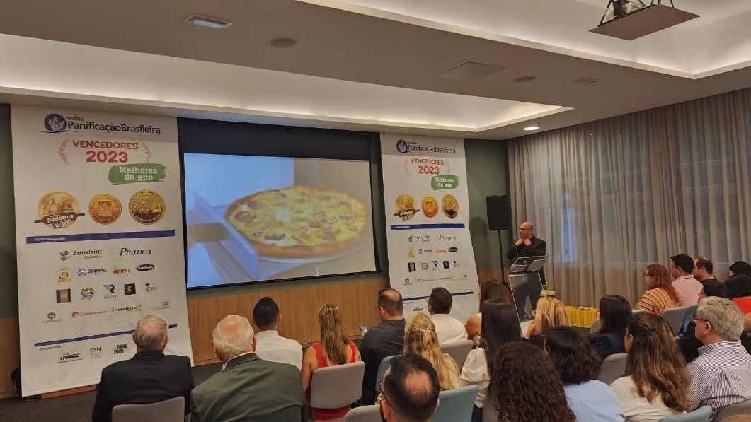 Um grupo de pessoas está sentado em uma sala assistindo a uma apresentação.