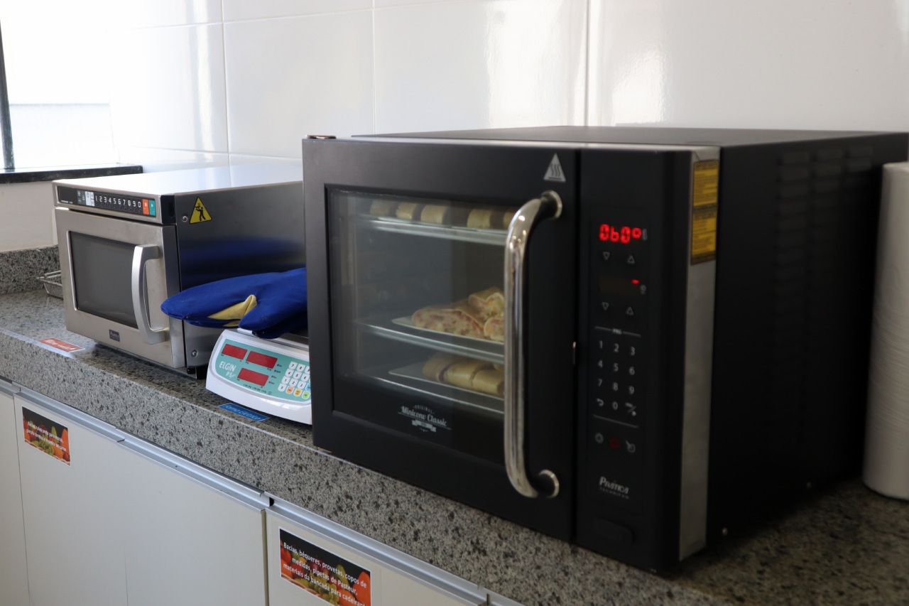 Um forno de micro-ondas está sobre um balcão ao lado de uma balança.