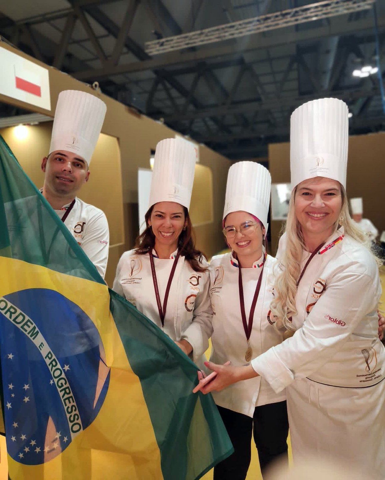 Um grupo de chefs segurando uma bandeira brasileira