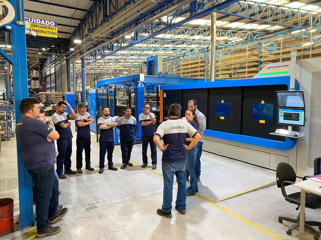 Um grupo de homens está em frente a uma máquina em uma fábrica.