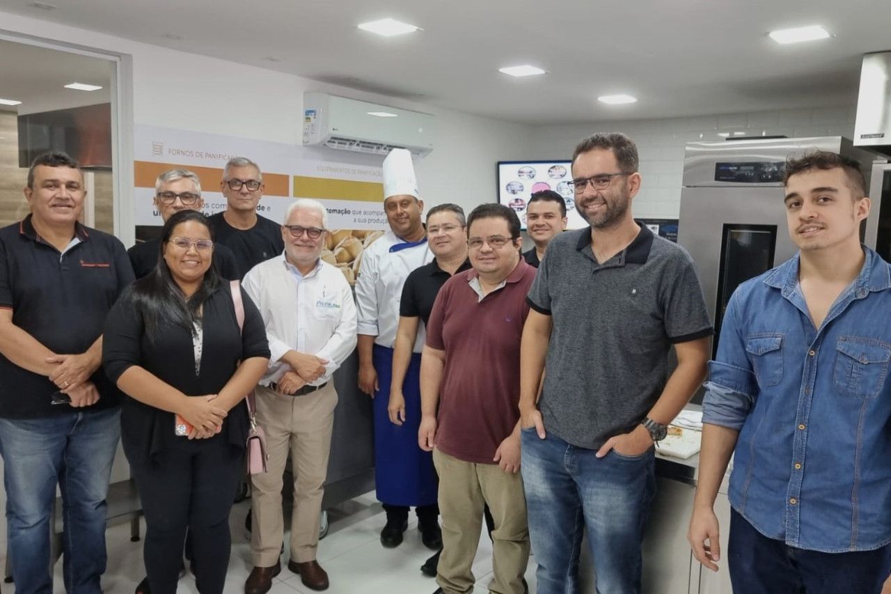 Um grupo de pessoas em pé, uma ao lado da outra, em uma sala.