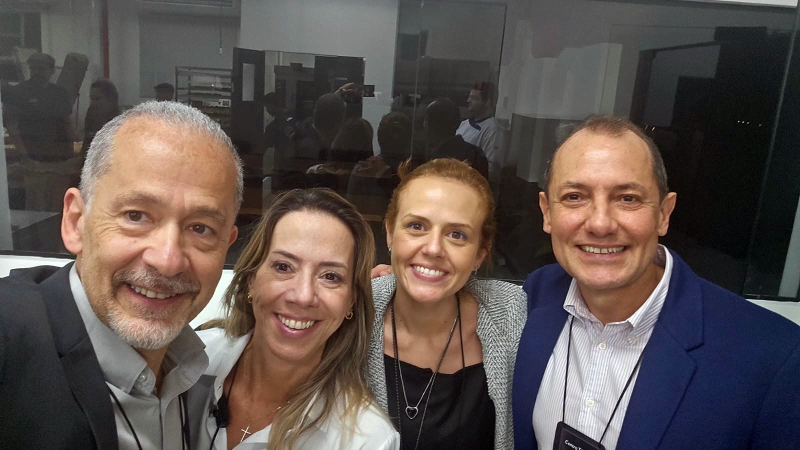 Quatro pessoas sorridentes posando juntas em um ambiente interno; duas mulheres e dois homens.