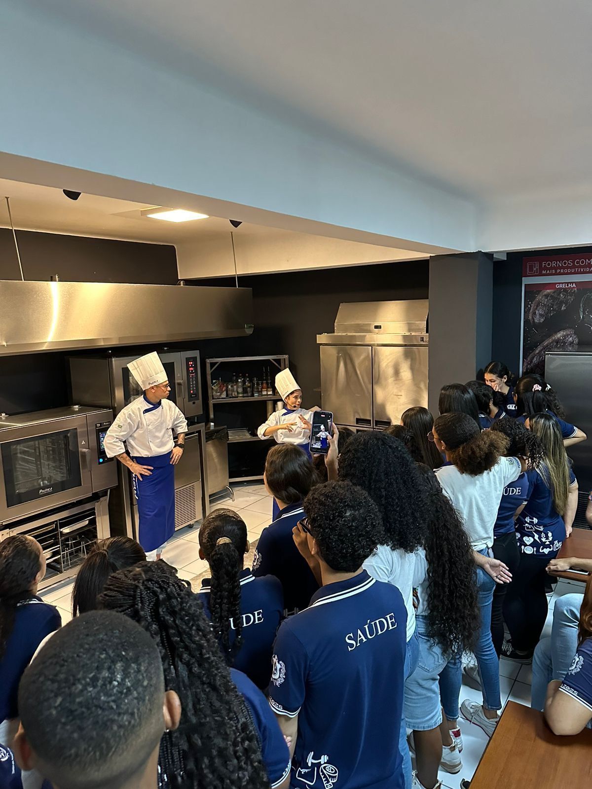 Um grupo de pessoas está sentado na cozinha observando um chef.