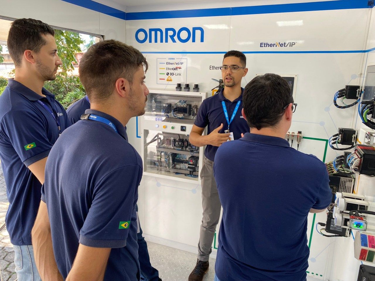 Um grupo de homens está em frente a uma placa que diz Omron.