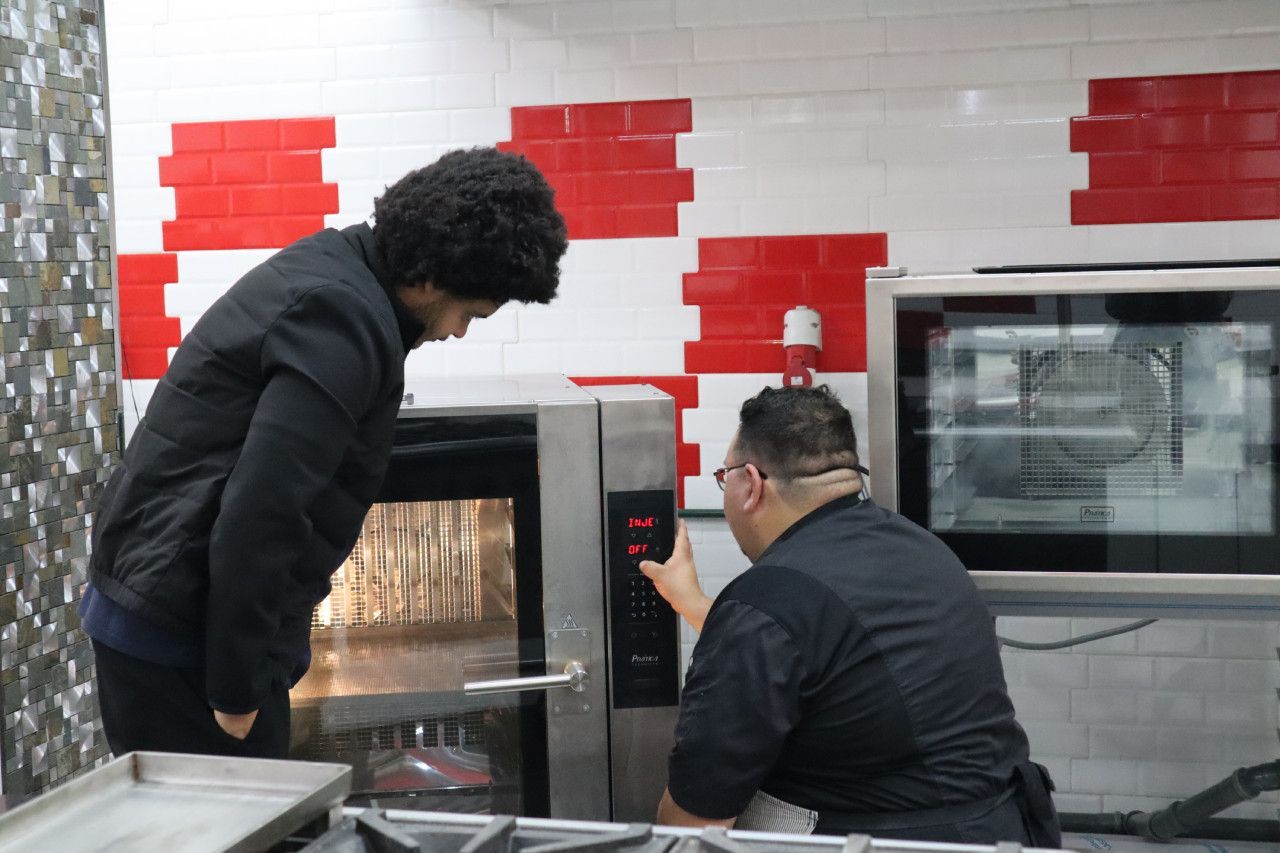 Dois homens estão olhando para um forno na cozinha.