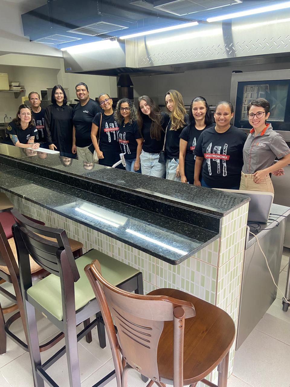 Um grupo de pessoas está posando para uma foto em uma cozinha.