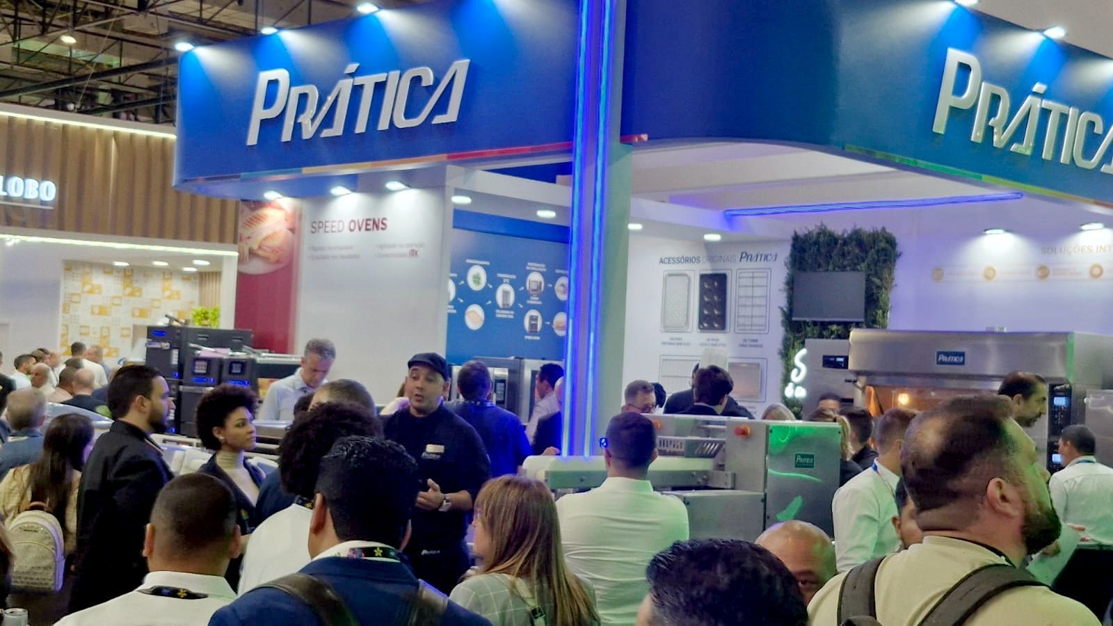 Um grande grupo de pessoas está em volta de um estande em uma convenção.