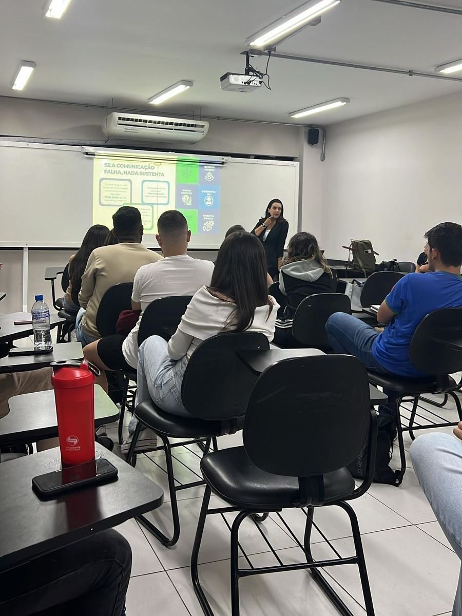 Um grupo de pessoas está sentado em uma sala de aula assistindo a uma apresentação.