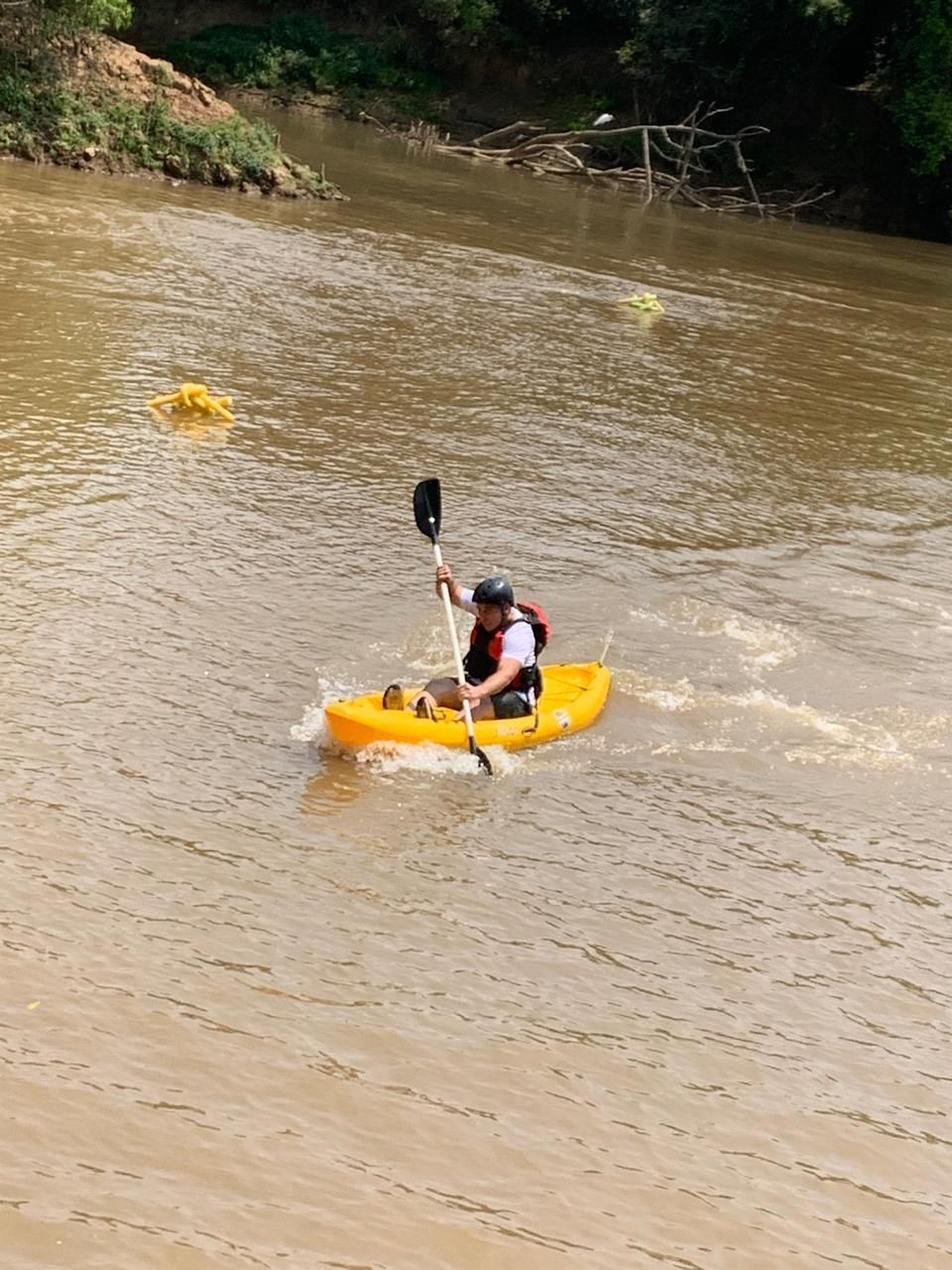 Um homem está remando um caiaque amarelo em um rio.