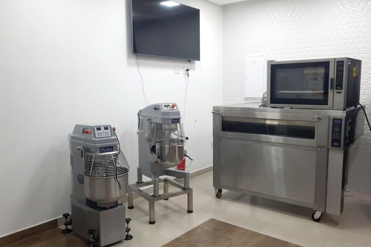 Uma cozinha com batedeira, forno, micro-ondas e televisão.