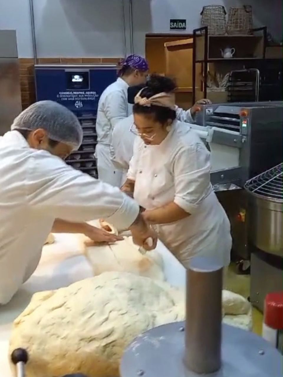 Um homem e uma mulher estão amassando massa na cozinha