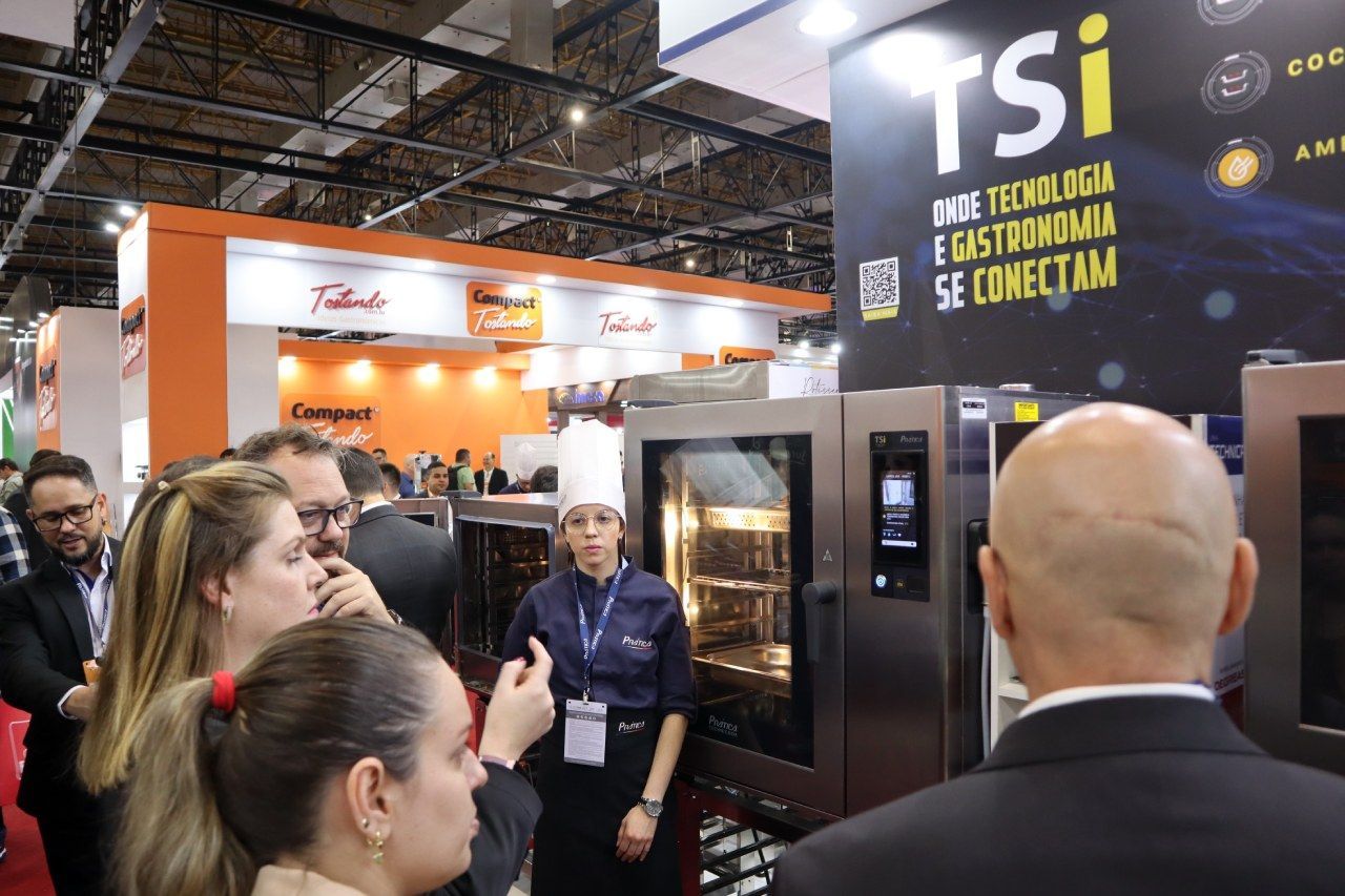 Um grupo de pessoas está em frente a uma placa que diz tsi.