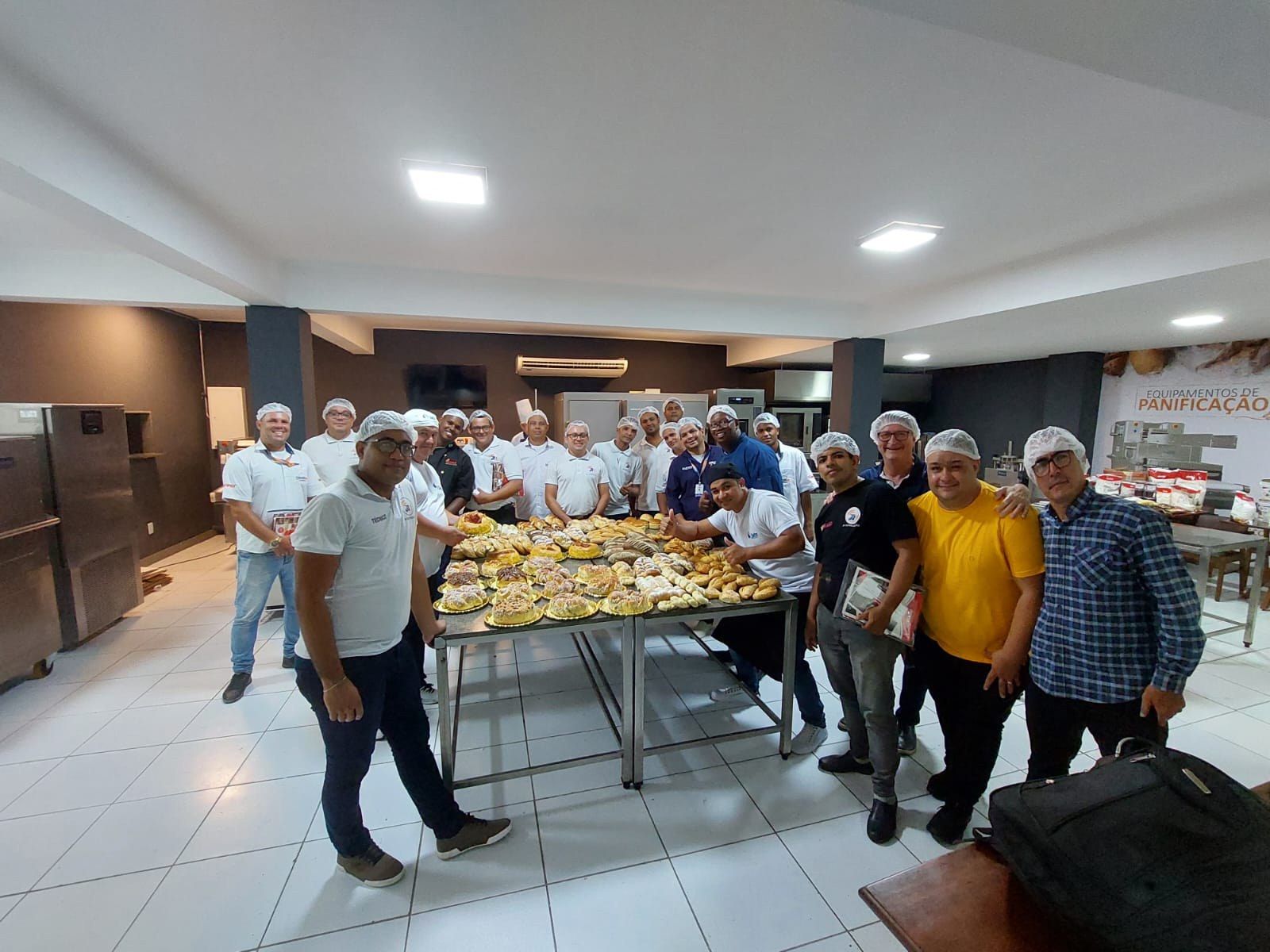 Um grupo de homens está em pé ao redor de uma mesa cheia de comida.