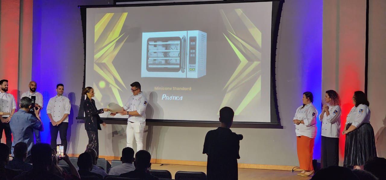 Um grupo de pessoas está em pé em frente a uma tela grande.