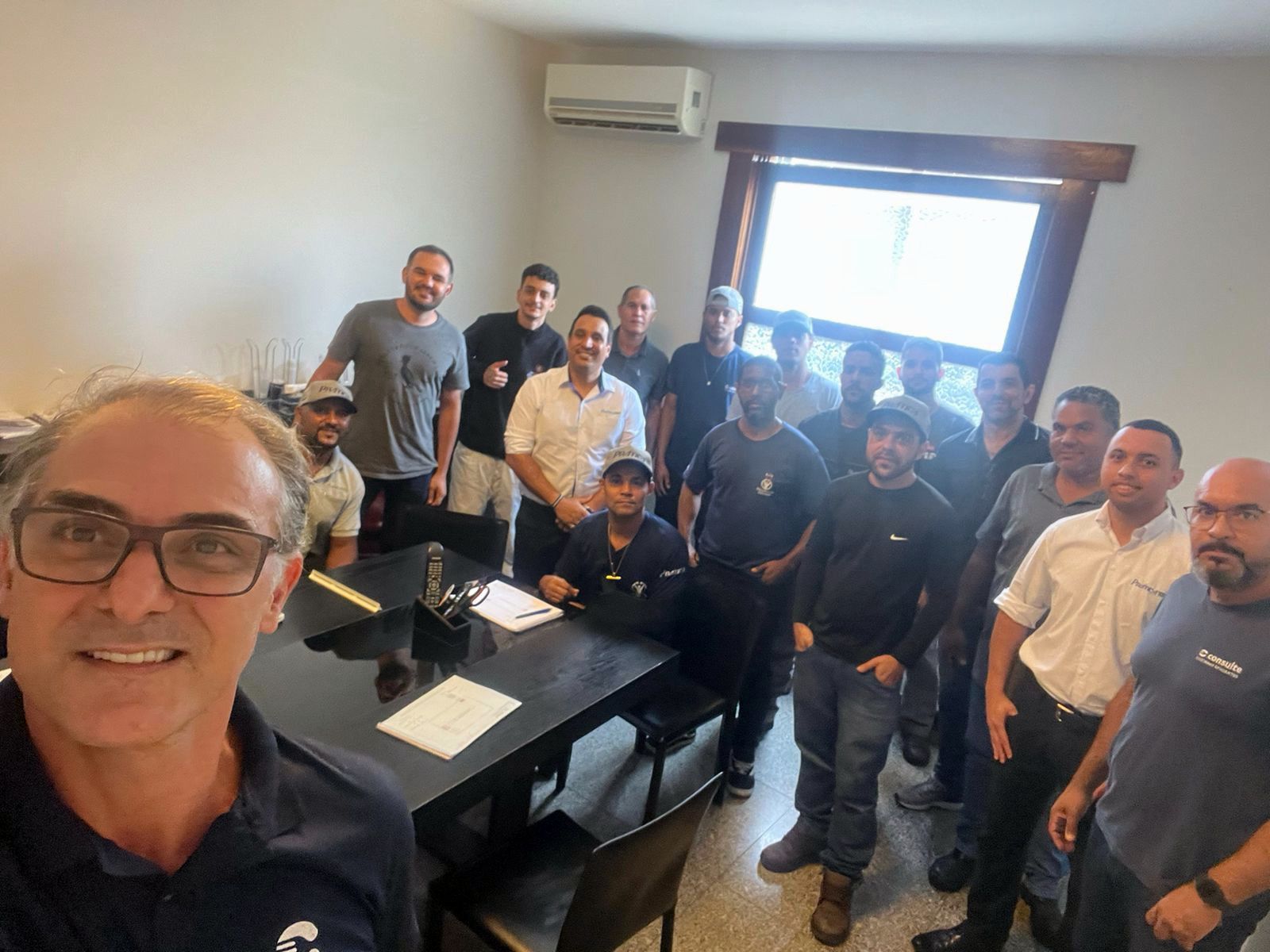 Um grupo de homens está posando para uma foto em uma sala.