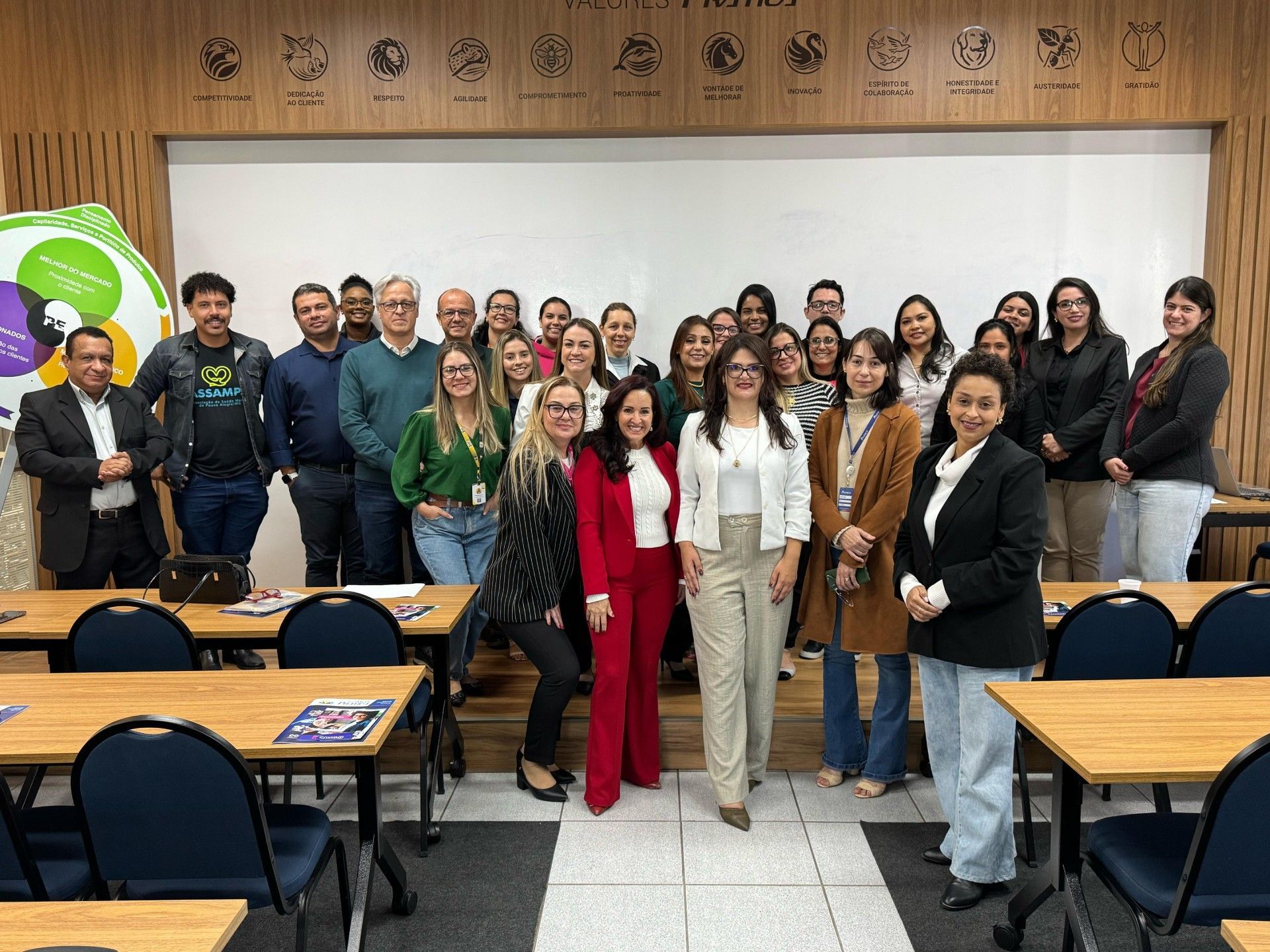 Um grupo de pessoas está posando para uma foto em uma sala de aula.