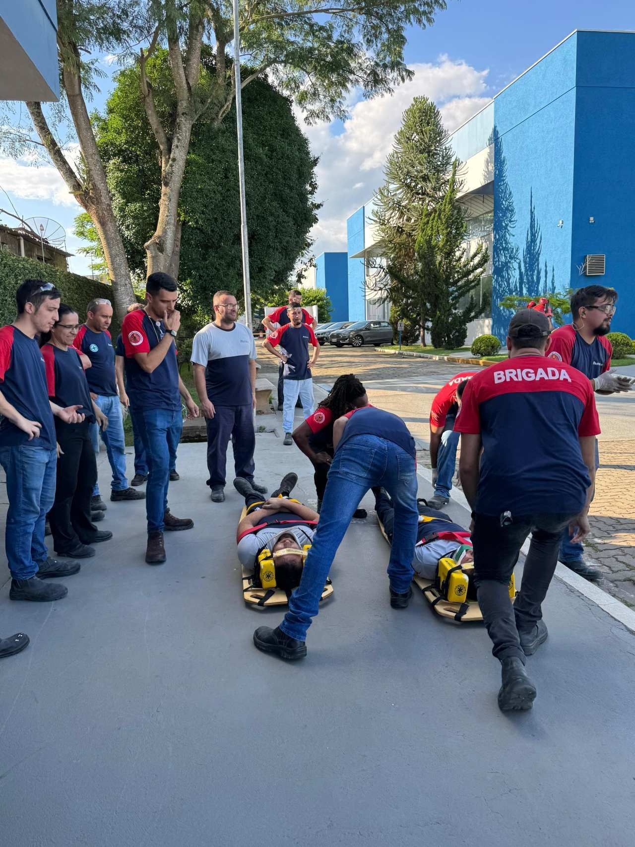 Um grupo de pessoas está em pé ao redor de um homem deitado no chão.