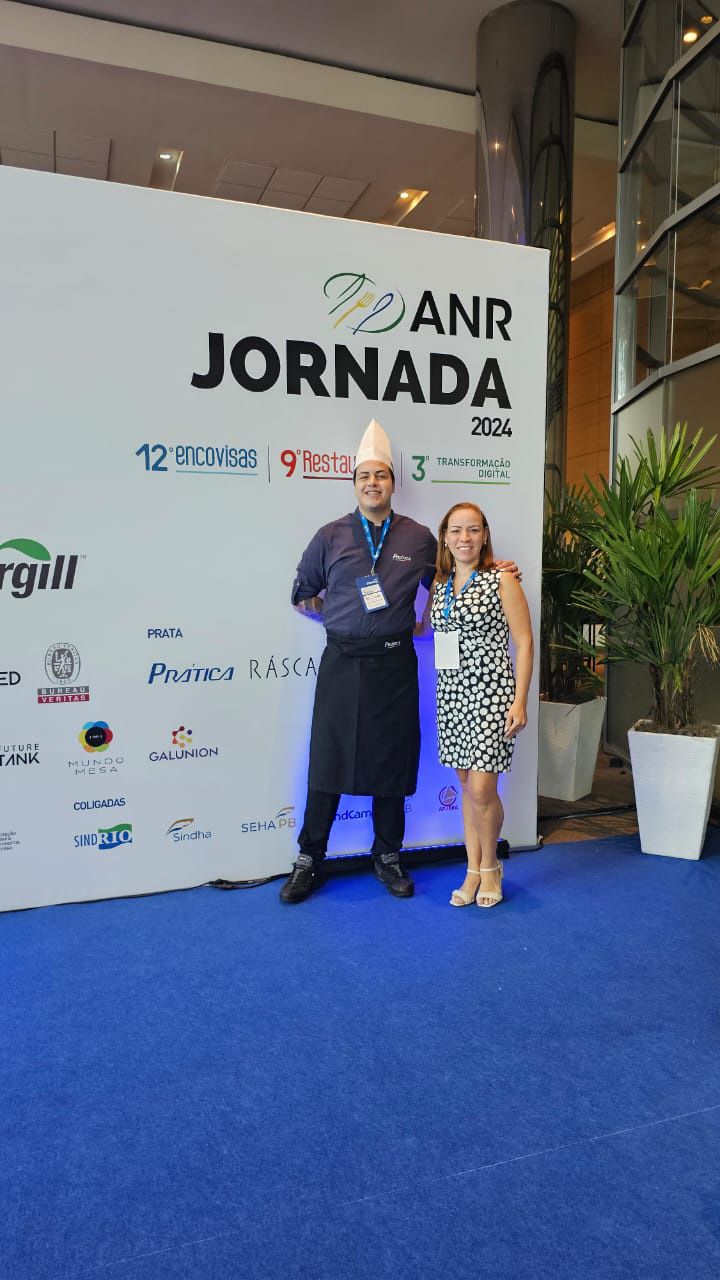 Um homem e uma mulher estão parados em frente a uma parede que diz anr jornada
