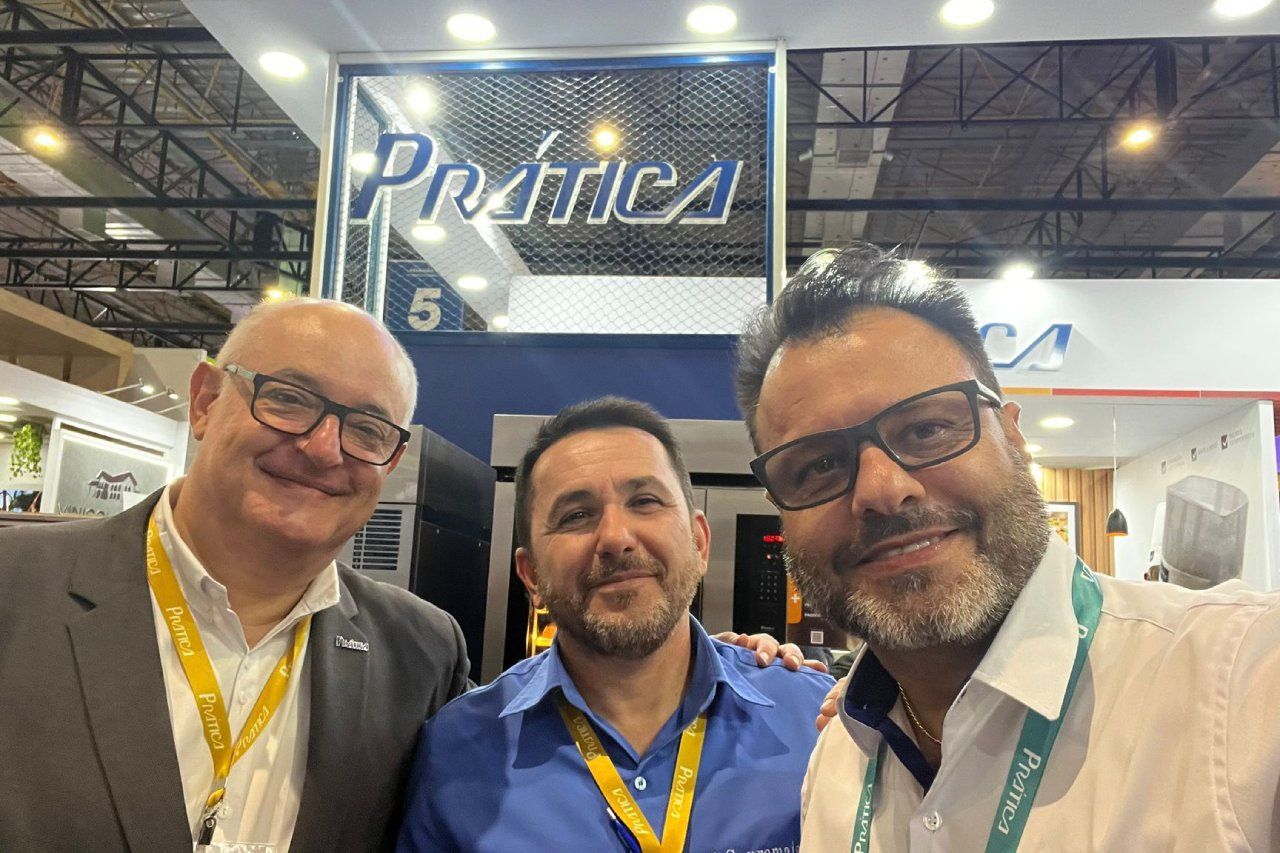 Três homens estão posando para uma foto em uma convenção.