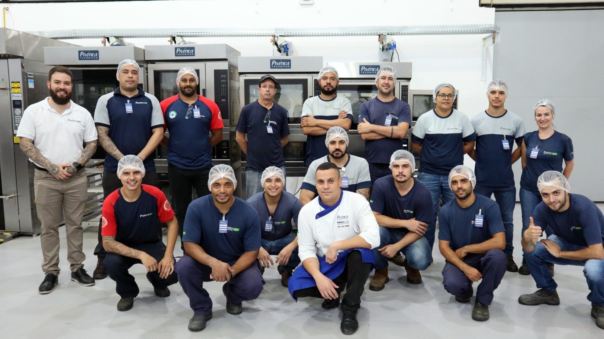 Um grupo de pessoas está posando para uma foto em uma cozinha.