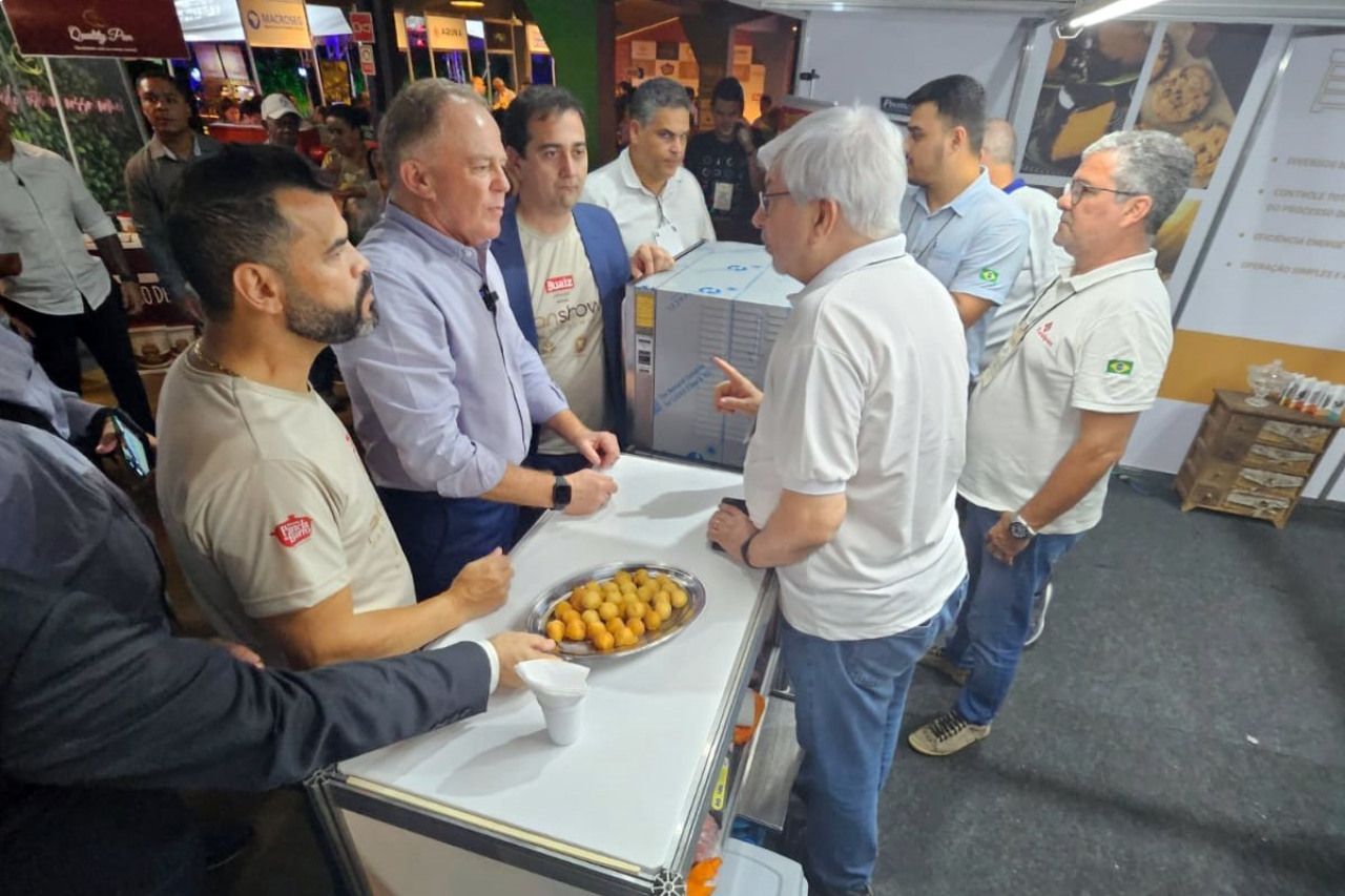 Um grupo de homens está em volta de uma mesa conversando entre si.