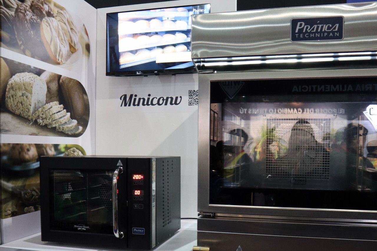 Um miniforno está sobre uma mesa ao lado de um forno de micro-ondas.