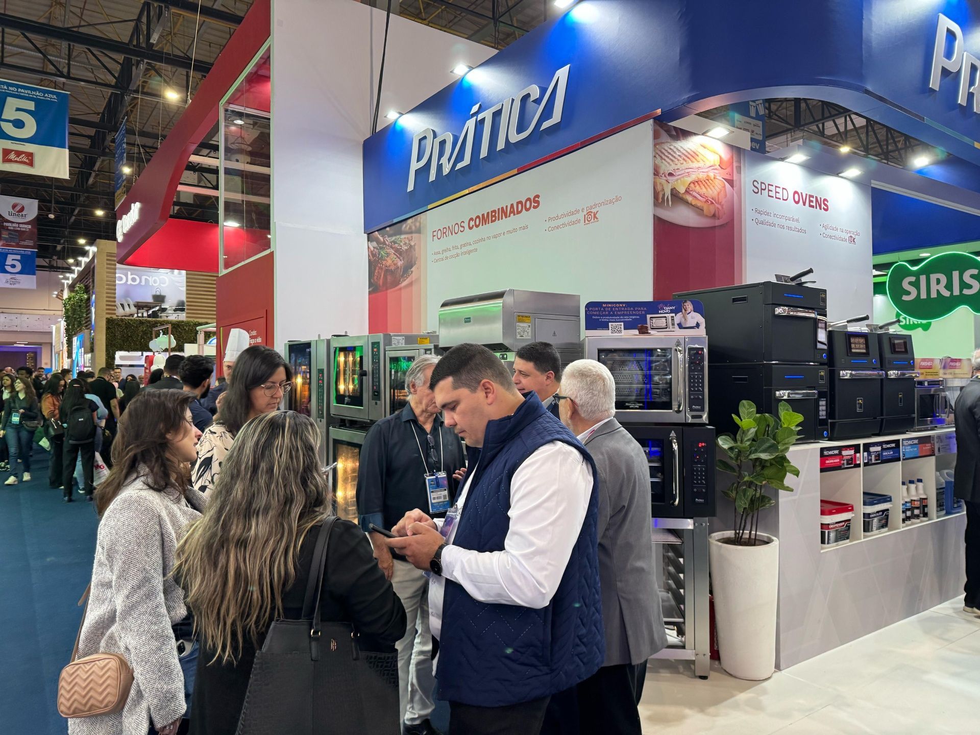 Um grupo de pessoas está em volta de um estande em uma convenção.