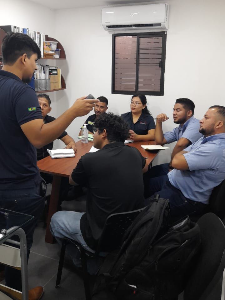 Um homem está fazendo uma apresentação para um grupo de pessoas sentadas ao redor de uma mesa