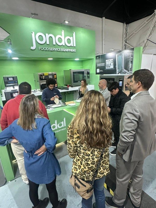 Um grupo de pessoas está em frente a uma placa verde que diz jondal.