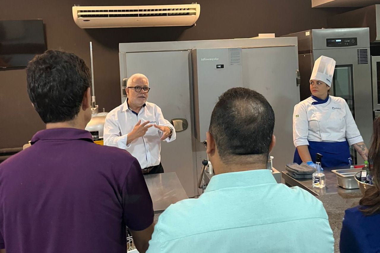 Um grupo de pessoas está em uma cozinha observando um chef.