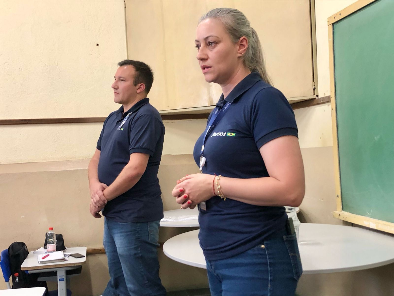 Um homem e uma mulher estão de pé, um ao lado do outro, em uma sala de aula.