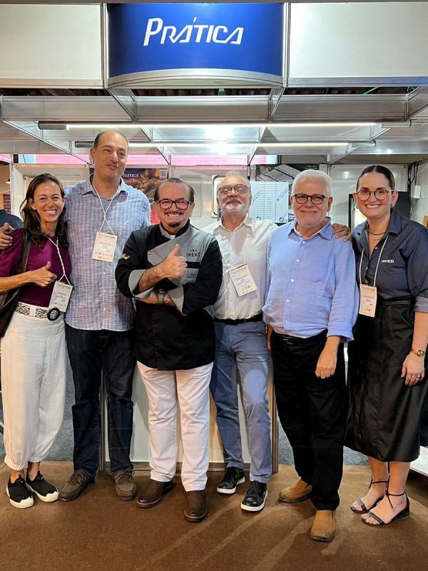 Um grupo de pessoas está posando para uma foto em frente a uma placa de prática.