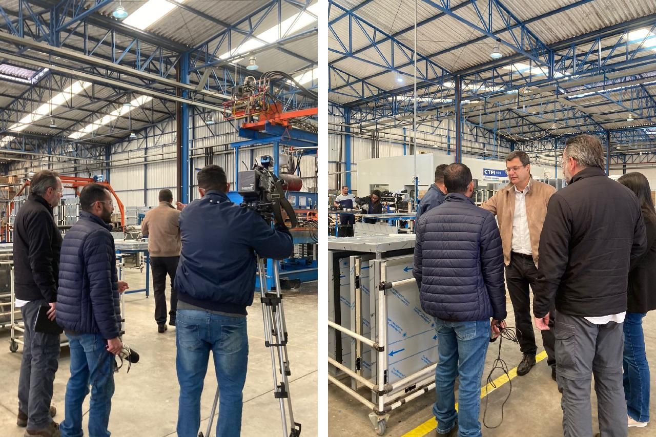 Um grupo de pessoas está em uma fábrica conversando entre si.