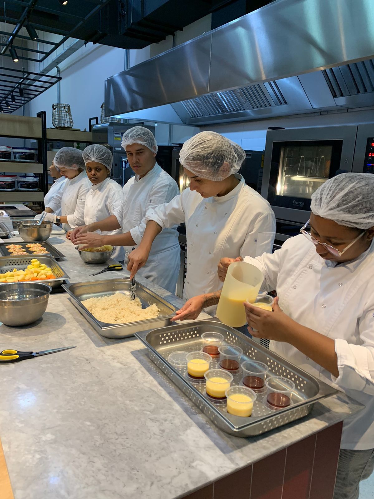 Um grupo de chefs está preparando comida em uma cozinha.