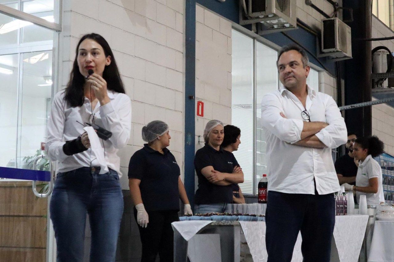 Uma mulher está falando em um microfone enquanto está ao lado de um homem.