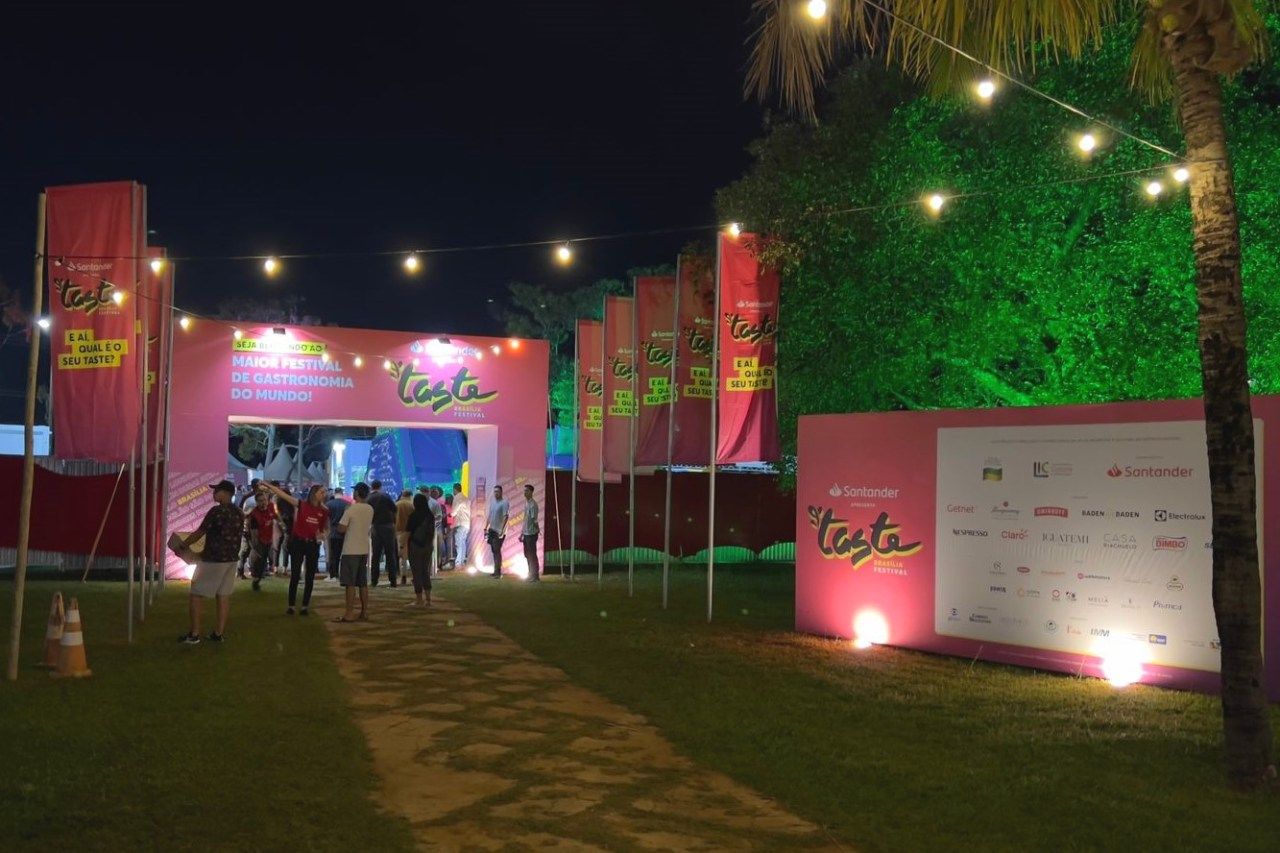 Um grupo de pessoas está caminhando por um caminho em frente a um prédio rosa à noite.