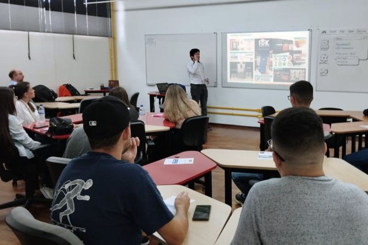 Um homem está fazendo uma apresentação para um grupo de alunos em uma sala de aula