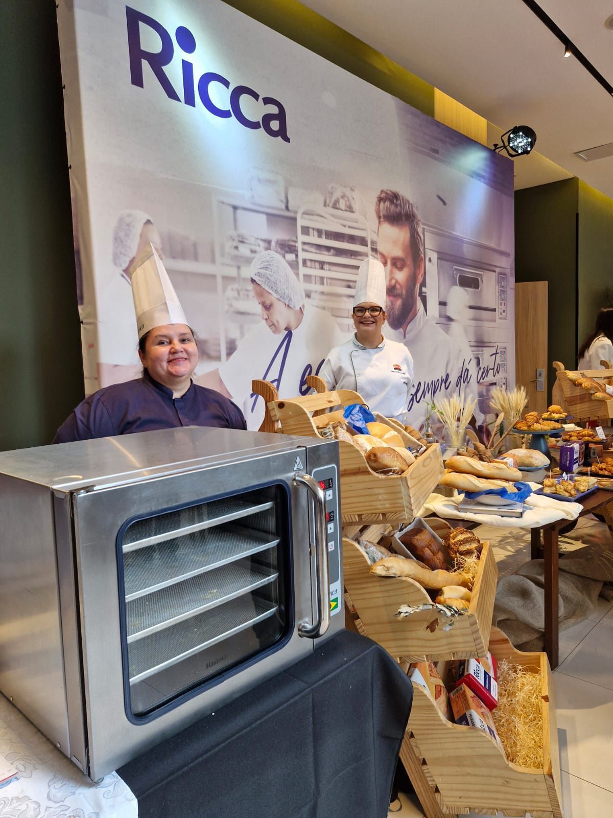 Uma mulher com um chapéu de chef está parada em frente a uma placa da ricca.