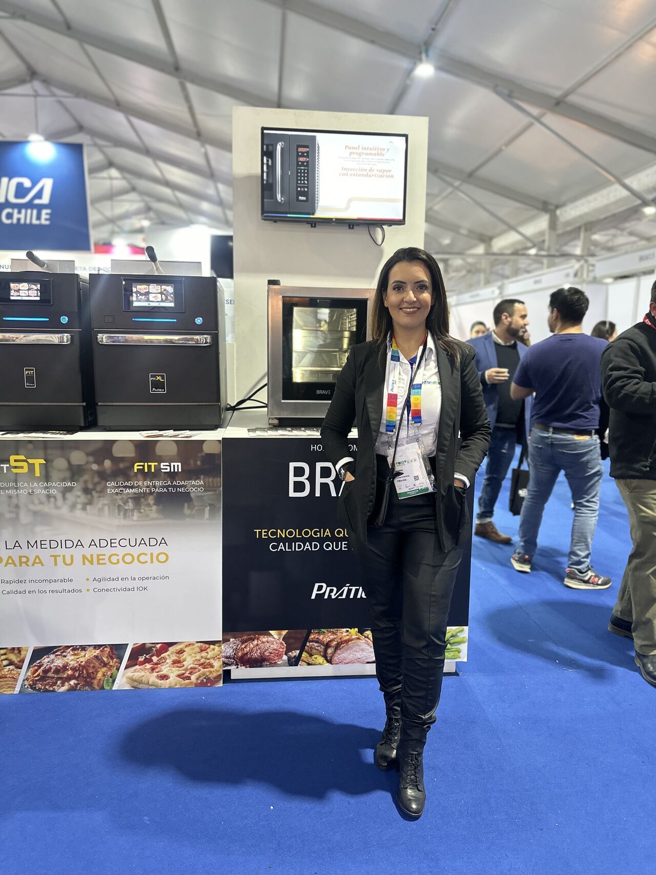 Uma mulher está parada em frente a um estande em uma convenção.