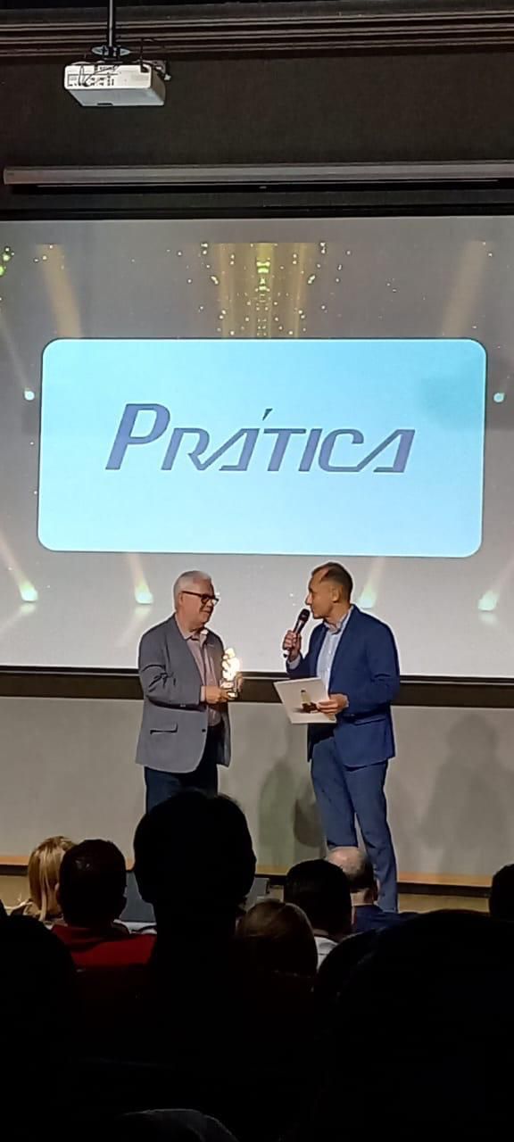 Dois homens estão em pé diante de uma tela grande com a palavra pratica escrita nela.
