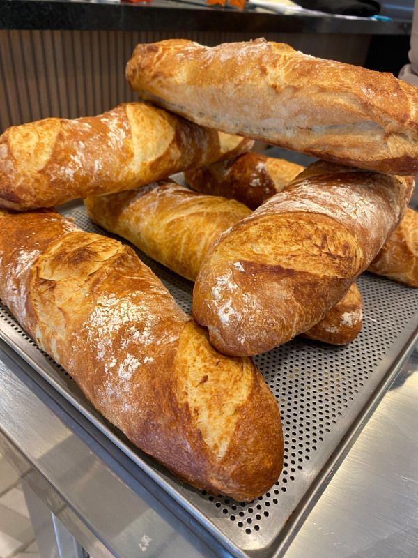 Um monte de baguetes estão em cima de uma bandeja de metal.