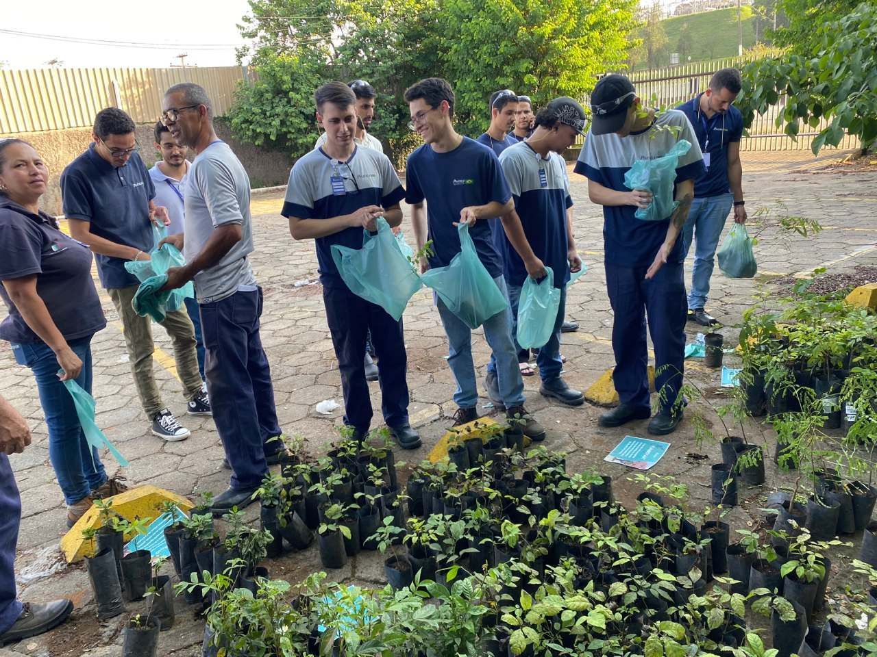 Um grupo de pessoas está em pé ao redor de um monte de plantas em vasos.