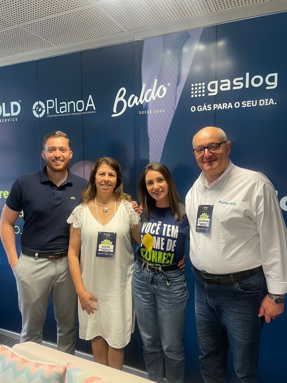 Um grupo de pessoas está posando para uma foto em frente a uma parede azul.
