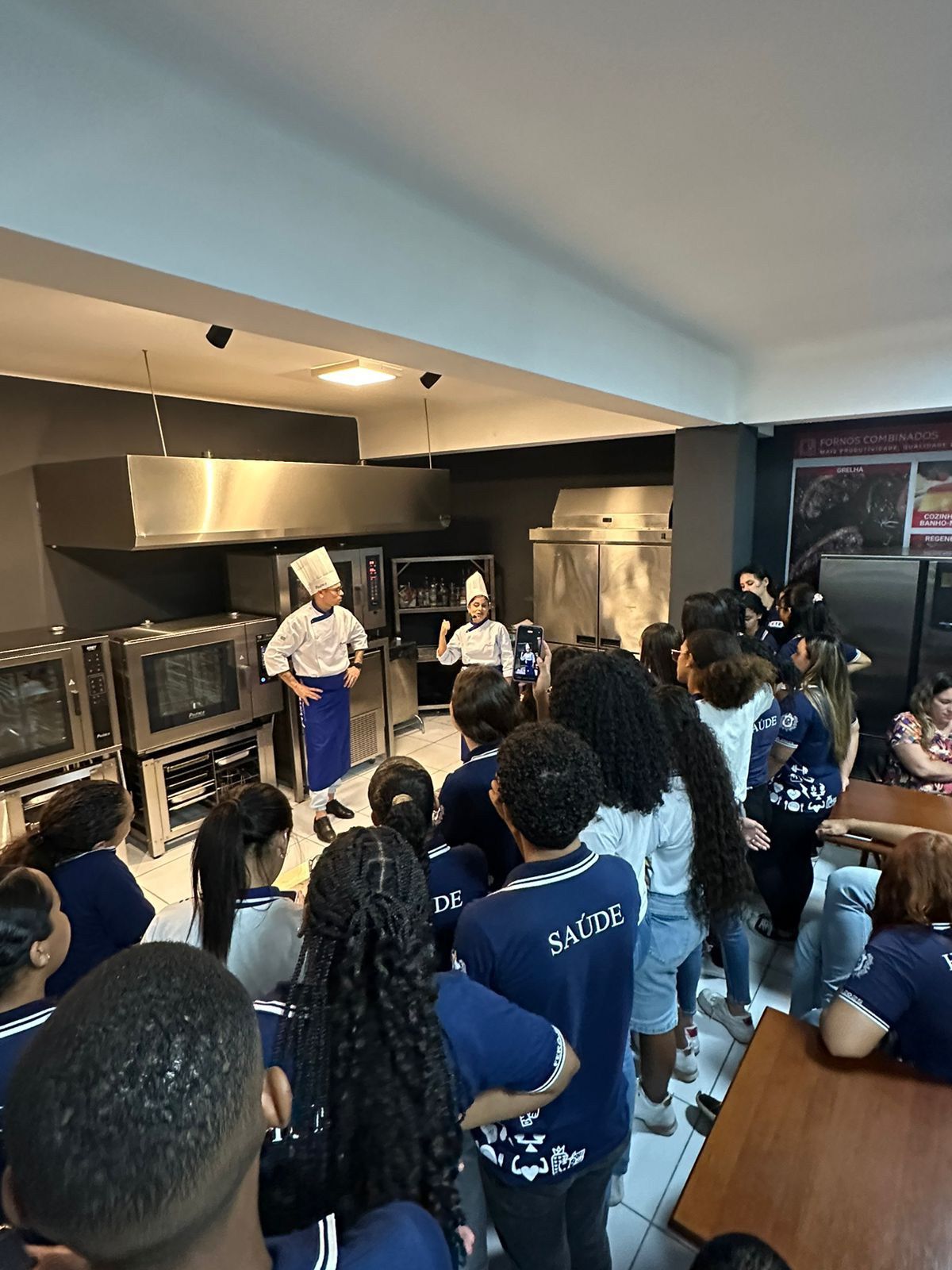Um grupo de pessoas está em uma cozinha observando um chef.