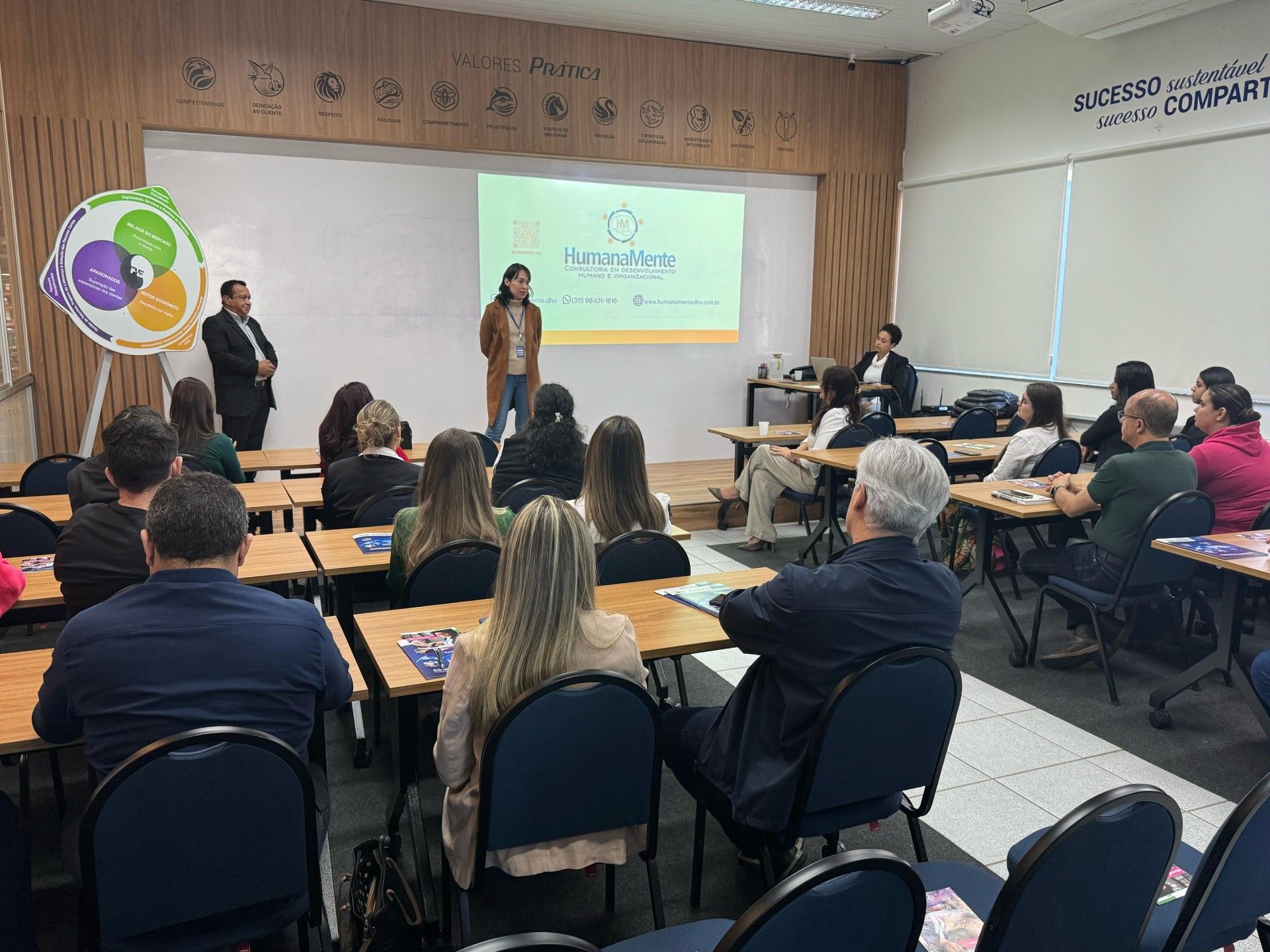 Um grupo de pessoas está sentado em uma sala de aula assistindo a uma apresentação.