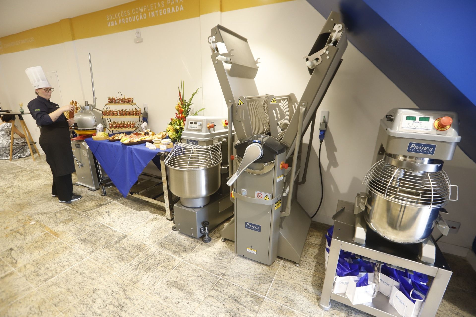 Chef em uma exposição de alimentos com misturadores industriais em uma cozinha comercial.